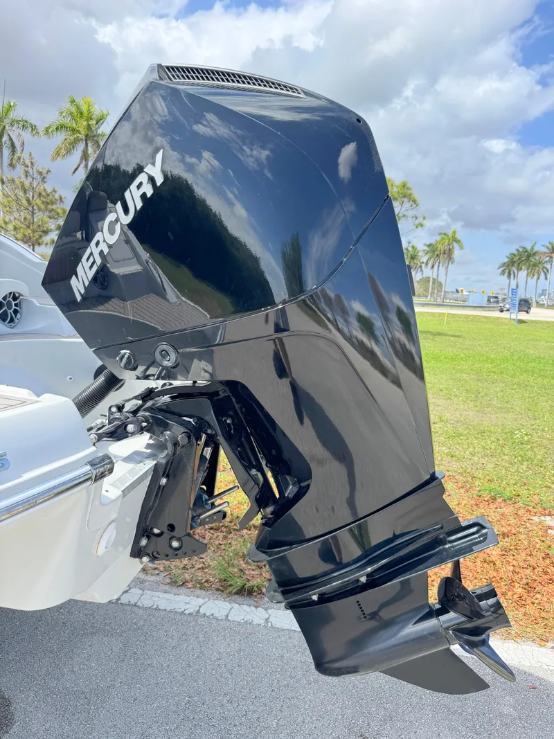 Slide: The Image of 2022 Crownline Eclipse E235 XS with Mercury outboard motor, parked outdoors under a cloudy sky. - 29
