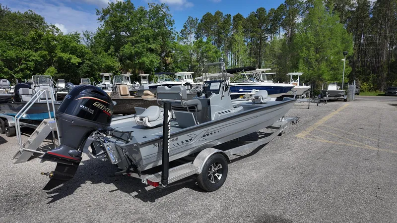 Slide: The Image of 2025 Xpress H20B boat on trailer in outdoor lot, surrounded by trees and other boats. - 17