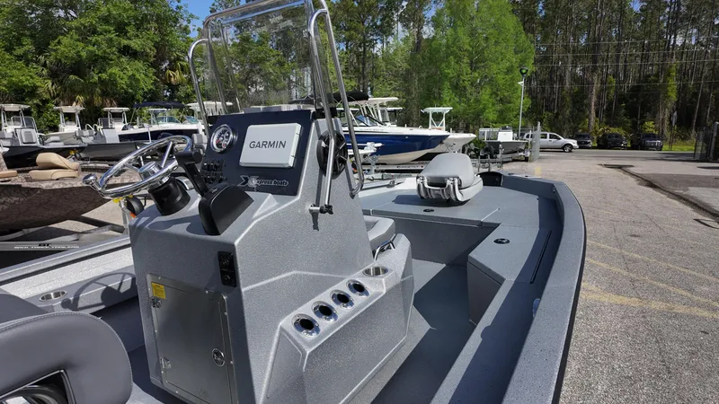 Slide: The Image of 2025 Xpress H20B boat with Garmin system, parked outdoors, surrounded by trees and other boats. - 21