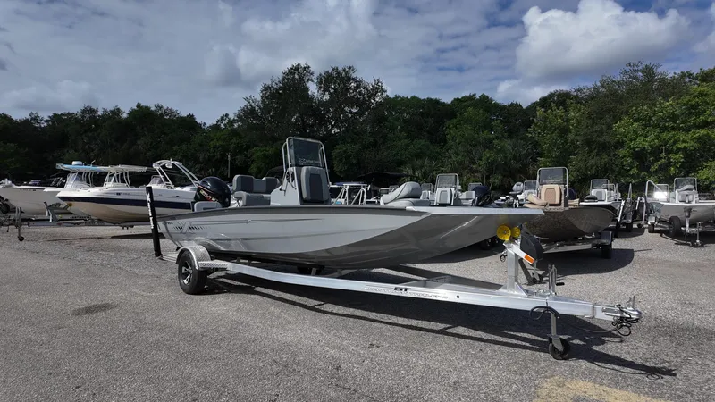 Slide: The Image of 2025 Xpress H20B boat on trailer in parking lot, surrounded by trees and other boats. - 4