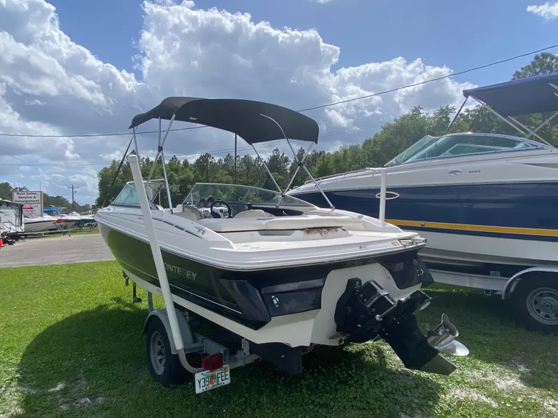 Slide: The Image of 2005 Monterey 194 BR boat on trailer with canopy, parked on grass under cloudy sky. - 3