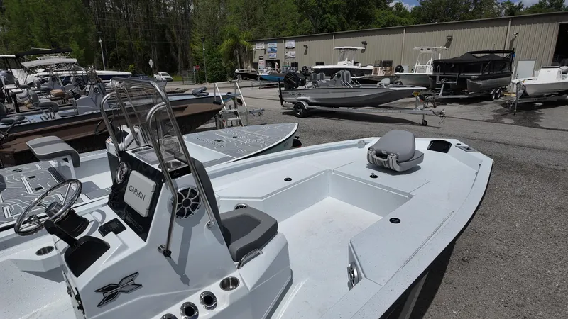 Slide: The Image of 2025 Xpress H22B boat displayed at a dealership with other boats in the background. - 18