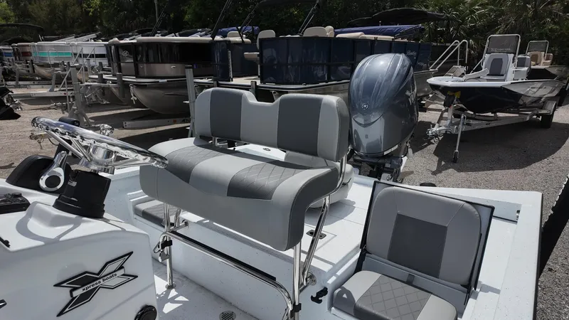 Slide: The Image of 2025 Xpress H22B boat with gray seating and motor, docked among other boats. - 26