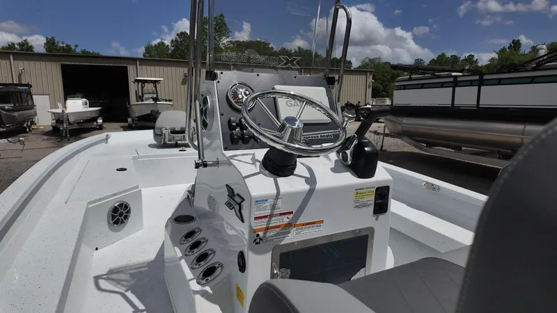 Slide: The Image of 2025 Xpress H22B boat interior with steering wheel and control panel, parked outdoors. - 28