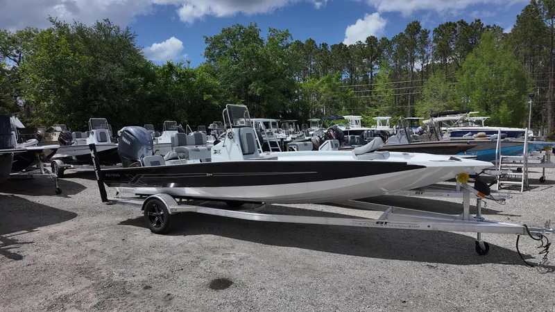 Slide: The Image of 2025 Xpress H22B boat on trailer, parked outdoors with trees and other boats in background. - 5