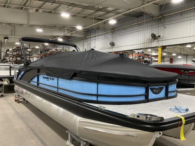 Slide: The Image of 2025 Bennington R Bowrider Swingback 24 RTSB pontoon boat with cover in a warehouse. - 15