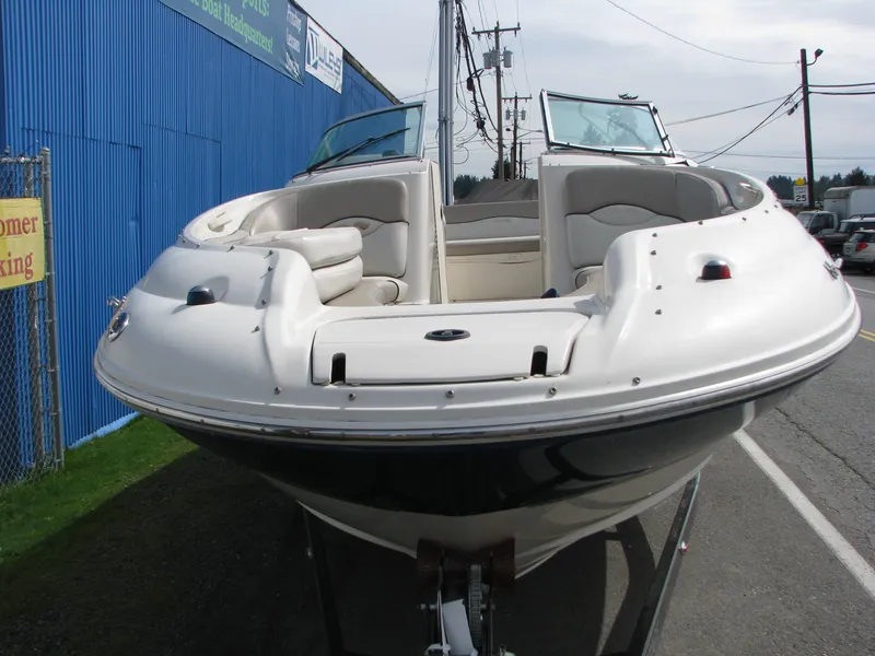 Slide: The Image of 2003 Sea Ray 240 Sundeck boat, white exterior, parked outdoors near a blue building. - 17