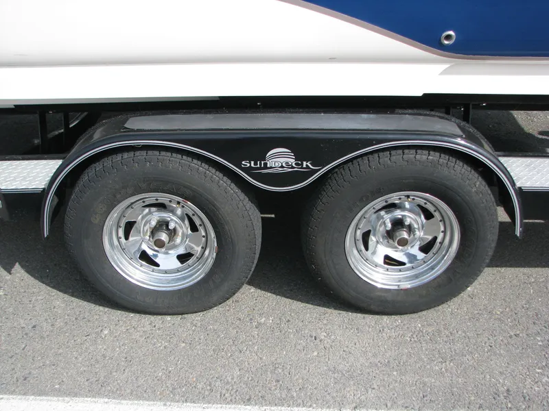 Slide: The Image of 2003 Sea Ray 240 Sundeck trailer wheels with chrome rims on asphalt. - 21
