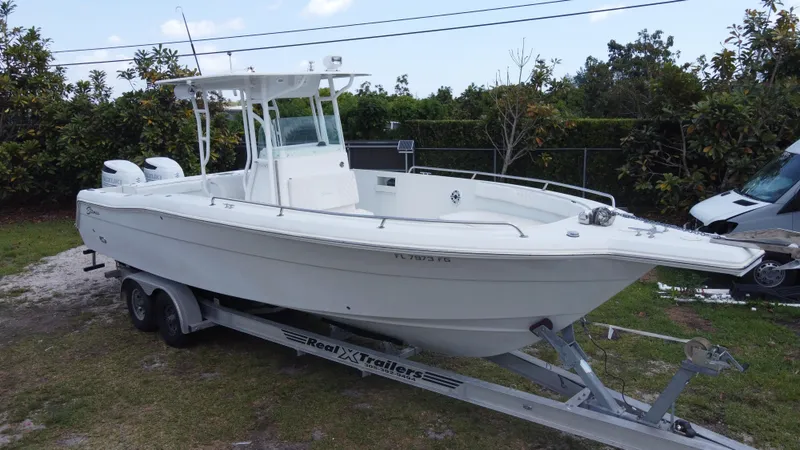 The Image of 1997 Stamas 290 Tarpon boat on trailer, white hull, dual engines, outdoor setting. - 0