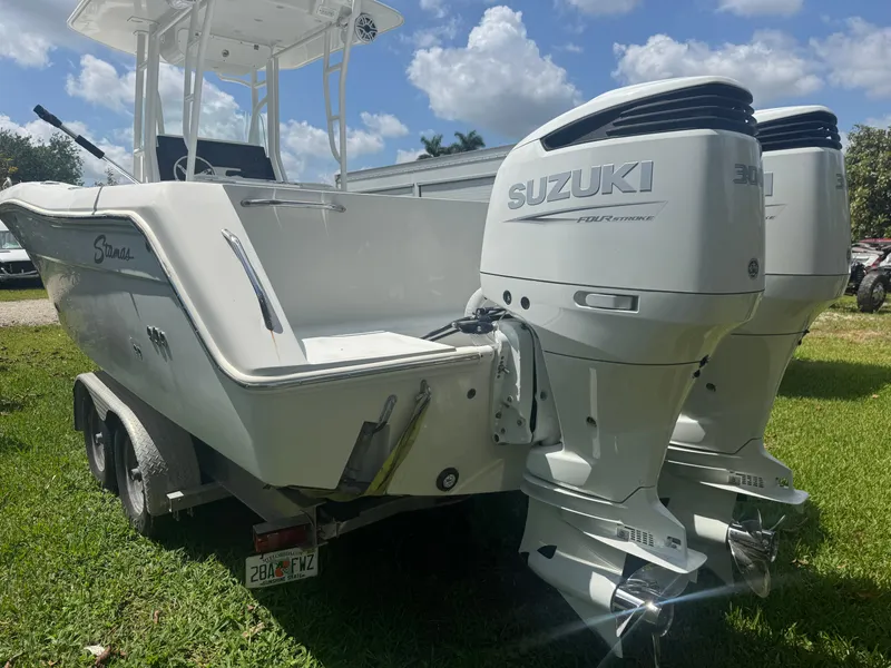 Slide: The Image of 1997 Stamas 290 Tarpon boat with dual Suzuki outboard motors on a grassy area. - 12