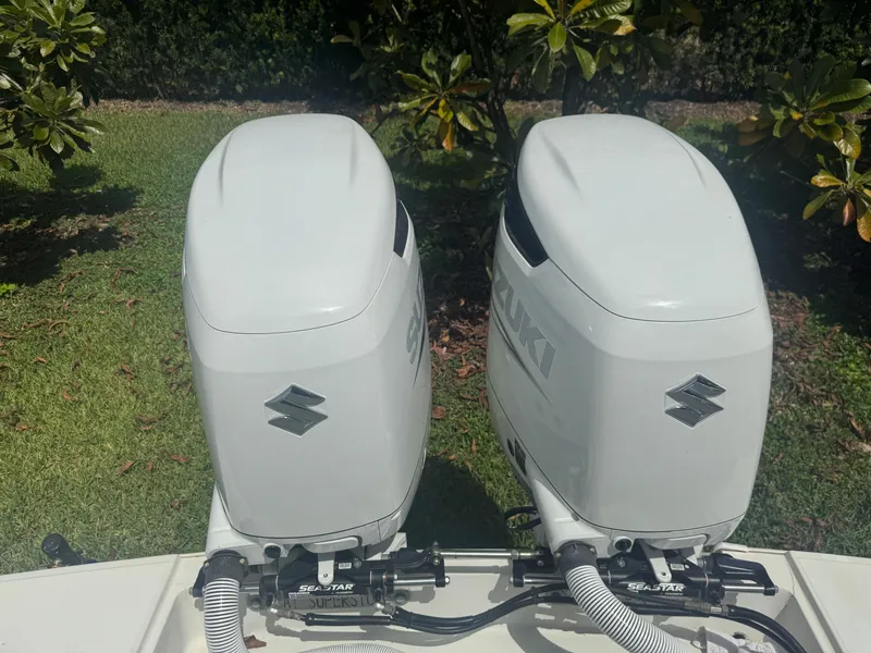 Slide: The Image of Twin Suzuki outboard motors on a 1997 Stamas 290 Tarpon boat, parked on grass. - 30