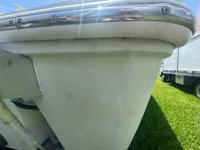 Slide: The Image of Close-up of a 1997 Stamas 290 Tarpon boat hull, showing metal trim and grassy background. - 38