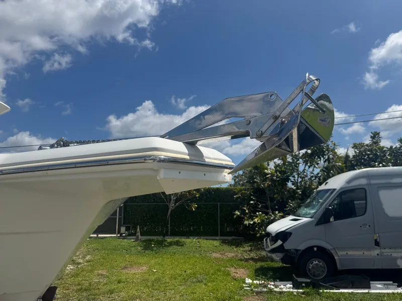 Slide: The Image of 1997 Stamas 290 Tarpon boat with anchor, parked near a white van under a blue sky. - 39