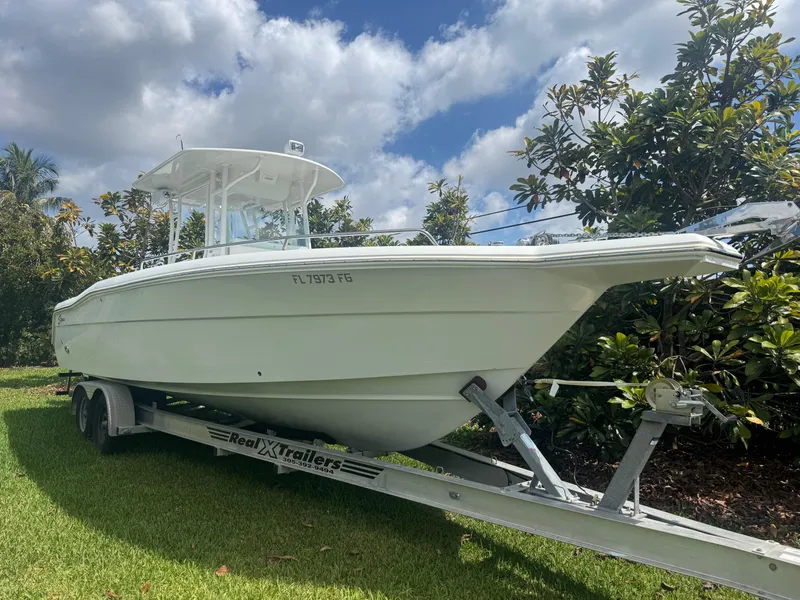 Slide: The Image of 1997 Stamas 290 Tarpon boat on trailer, parked on grass under a partly cloudy sky. - 8