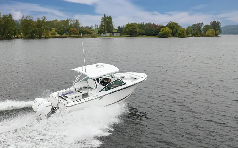 Slide: The Image of 2024 Blackfin 272 DC boat cruising on a scenic lake with lush greenery. - 7