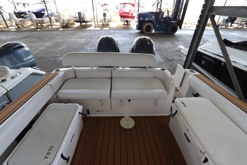 Slide: The Image of 2016 Robalo R265 Walkaround boat interior with seating and storage in a marina setting. - 10