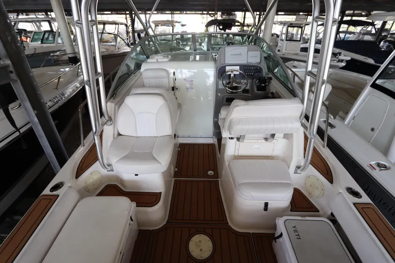 Slide: The Image of 2016 Robalo R265 Walkaround boat interior with white seating and wood flooring in a marina. - 21