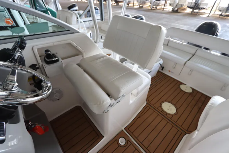 Slide: The Image of 2016 Robalo R265 Walkaround boat interior with white seating and wood-patterned flooring. - 24