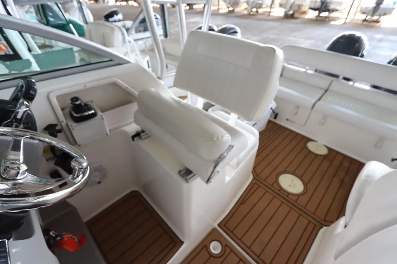 Slide: The Image of 2016 Robalo R265 Walkaround boat interior with white seating and wood-patterned flooring. - 25