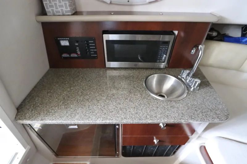 Slide: The Image of 2016 Robalo R265 Walkaround boat kitchenette with granite countertop, sink, and microwave. - 42