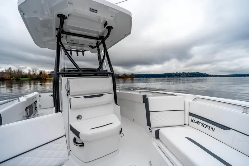 Slide: The Image of 2023 Blackfin 252 CC boat interior with white seating on a calm lake. - 16