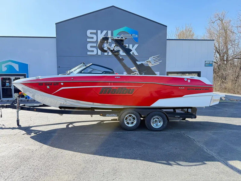 Slide: The Image of 2021 Malibu Wakesetter 23 LSV boat in red, parked on a trailer outside Ski Shack. - 0