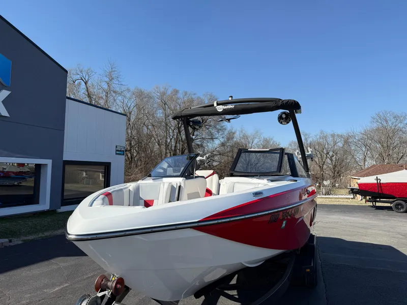 Slide: The Image of 2021 Malibu Wakesetter 23 LSV boat with red and white design, parked outdoors. - 2