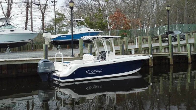 Slide: The Image of 2020 Robalo R242 Explorer boat docked by a wooden pier in a calm marina. - 8