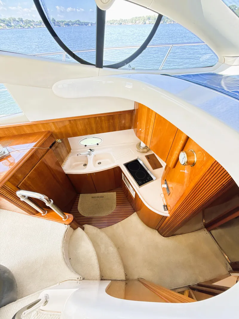 Slide: The Image of Interior view of 2002 Azimut 42 yacht, featuring a compact kitchen with wooden cabinetry. - 17