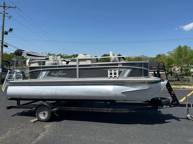 Slide: The Image of 2020 SunChaser Vista 18 Fish pontoon boat on trailer, parked outdoors. - 0