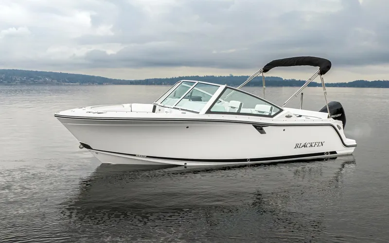 Slide: The Image of 2024 Blackfin 232DC Dual Console boat on calm water under cloudy skies. - 0