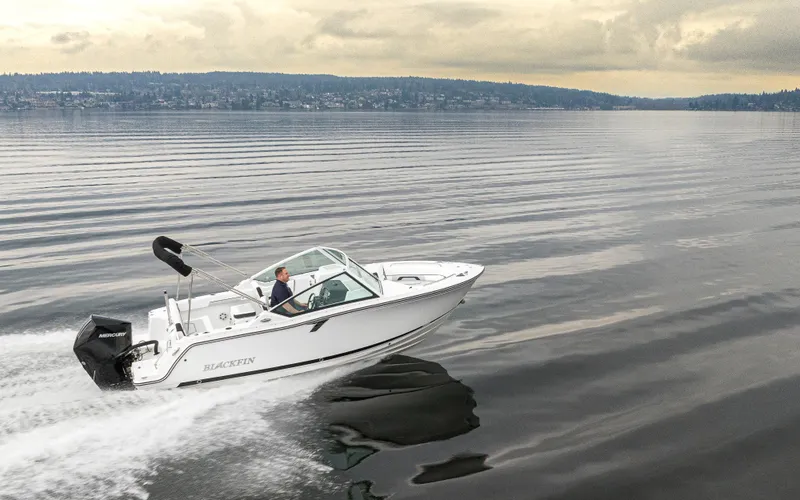 Slide: The Image of 2024 Blackfin 232DC Dual Console boat cruising on calm waters under cloudy skies. - 38