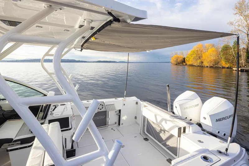 Slide: The Image of 2024 Blackfin 252 DC boat on serene lake with autumn trees and dual Mercury engines. - 36