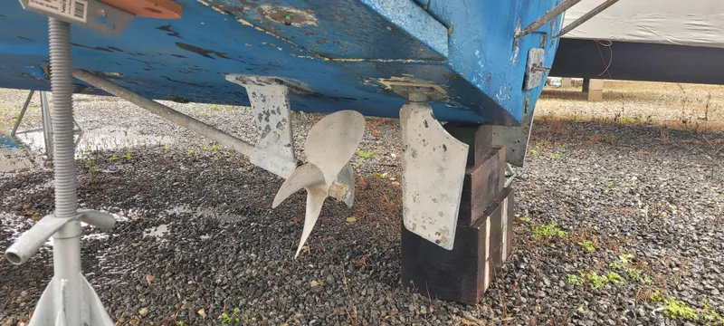 Slide: The Image of 2006 Wellcraft 330 Coastal boat underside with propeller and rudder on gravel. - 20