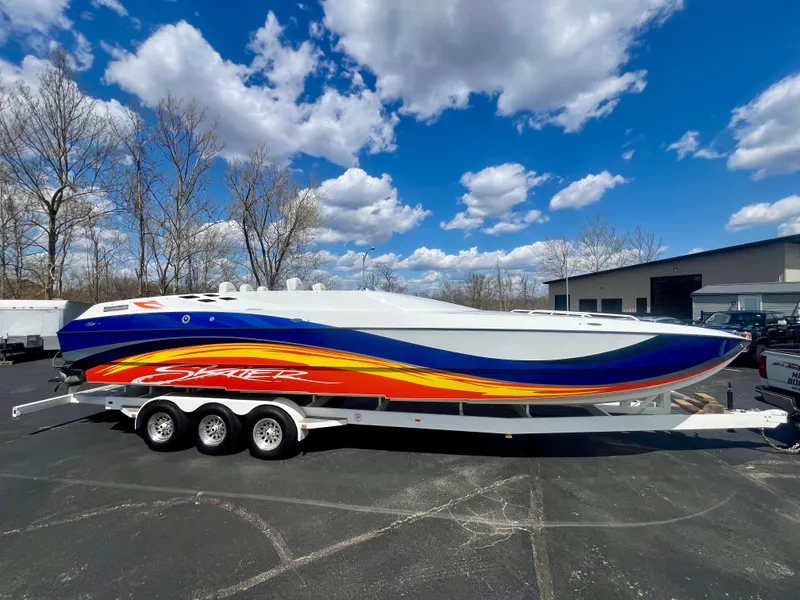 Slide: The Image of 2001 Skater 32B powerboat with vibrant graphics on a trailer under a blue sky. - 0