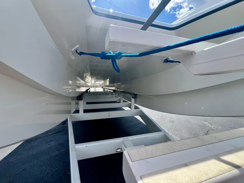 Slide: The Image of Underneath view of a 2001 Skater 32B boat on a trailer, featuring blue rope and clear sky. - 32