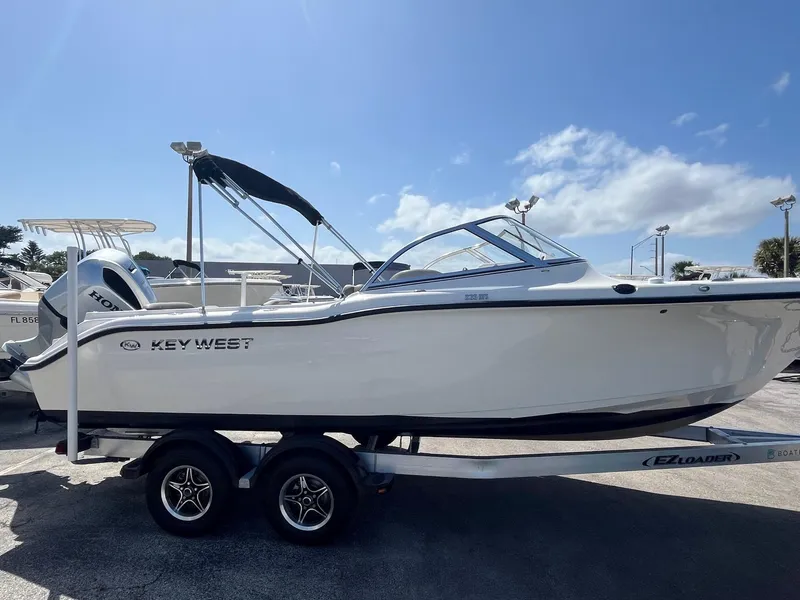 Slide: The Image of 2022 Key West 239 DFS boat on trailer under clear blue sky. - 0