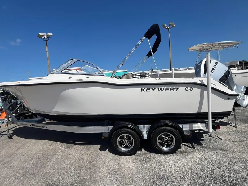 Slide: The Image of 2022 Key West 239 DFS boat on trailer, displayed outdoors under clear blue sky. - 1