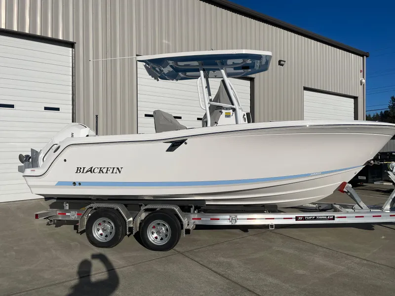 Slide: The Image of 2024 Blackfin 222 CC boat on trailer, parked outside a warehouse. - 1