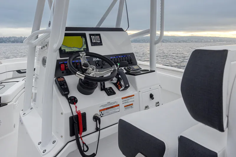 Slide: The Image of 2024 Blackfin 222 CC boat console with steering wheel and navigation display on the water. - 11