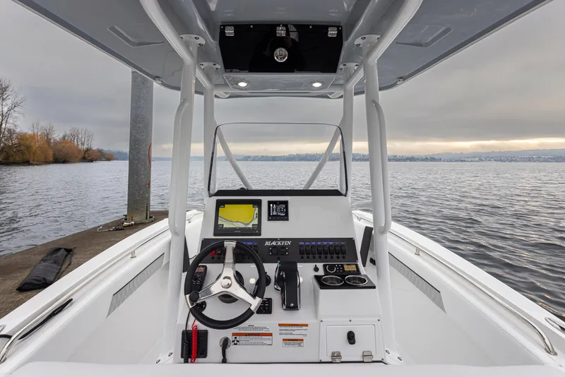 Slide: The Image of 2024 Blackfin 222 CC boat console with steering wheel and navigation system on a calm lake. - 17