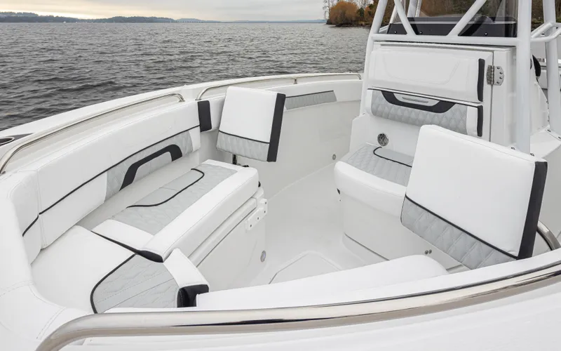 Slide: The Image of 2024 Blackfin 222 CC boat interior with white cushioned seating, on a calm lake. - 23