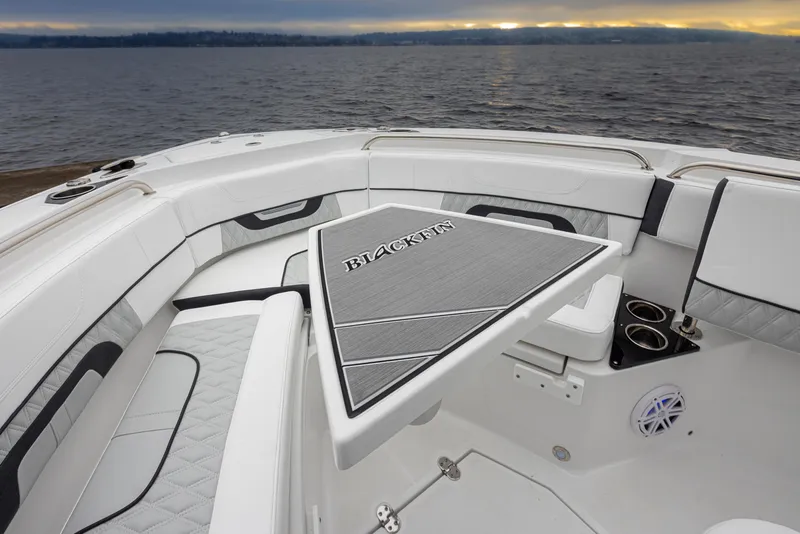 Slide: The Image of 2024 Blackfin 222 CC boat interior with sleek seating and table, overlooking calm waters. - 26