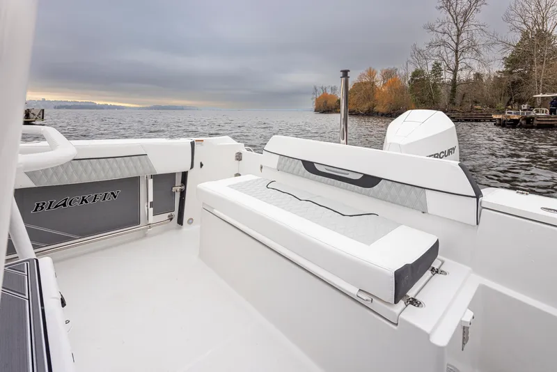 Slide: The Image of 2024 Blackfin 222 CC boat interior with seating, on a calm lake under cloudy skies. - 30