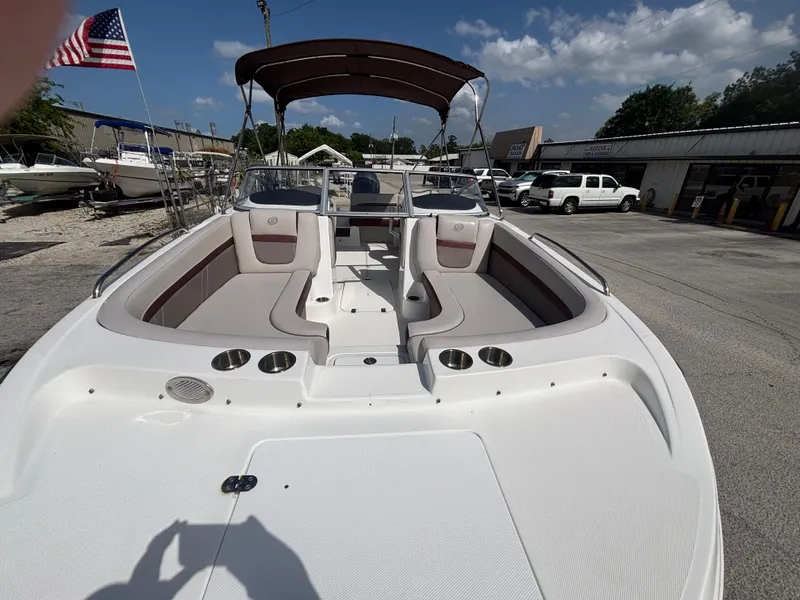 Slide: The Image of 2019 Hurricane SD217 boat with seating, cup holders, and canopy, parked outdoors under a blue sky. - 12