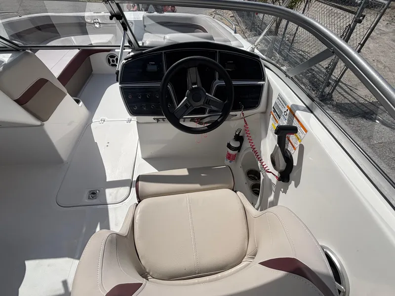 Slide: The Image of 2019 Hurricane SD217 boat cockpit with steering wheel, beige seating, and control panel. - 25