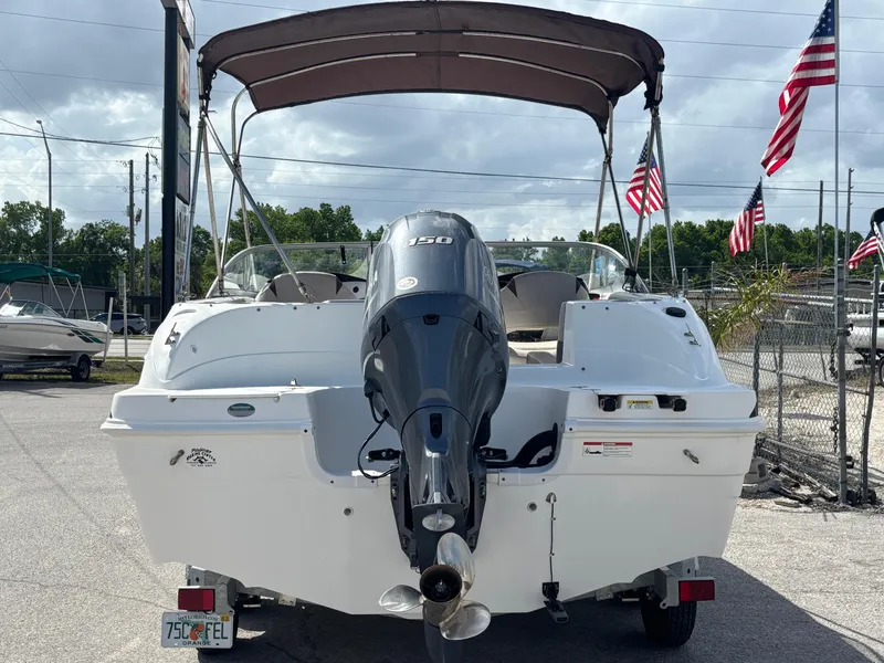 Slide: The Image of 2019 Hurricane SD217 boat with outboard motor and canopy, parked near American flags. - 5