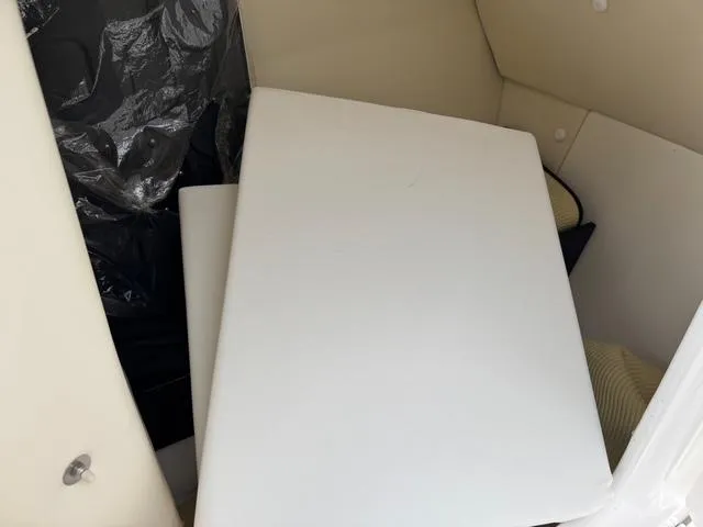 Slide: The Image of 2016 Yamaha Boats 242 Limited S interior storage area with white cushions. - 7