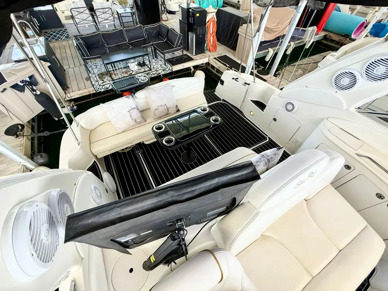 Slide: The Image of 1999 Sea Ray 340 Sundancer cockpit with seating, table, and speakers at a marina. - 16