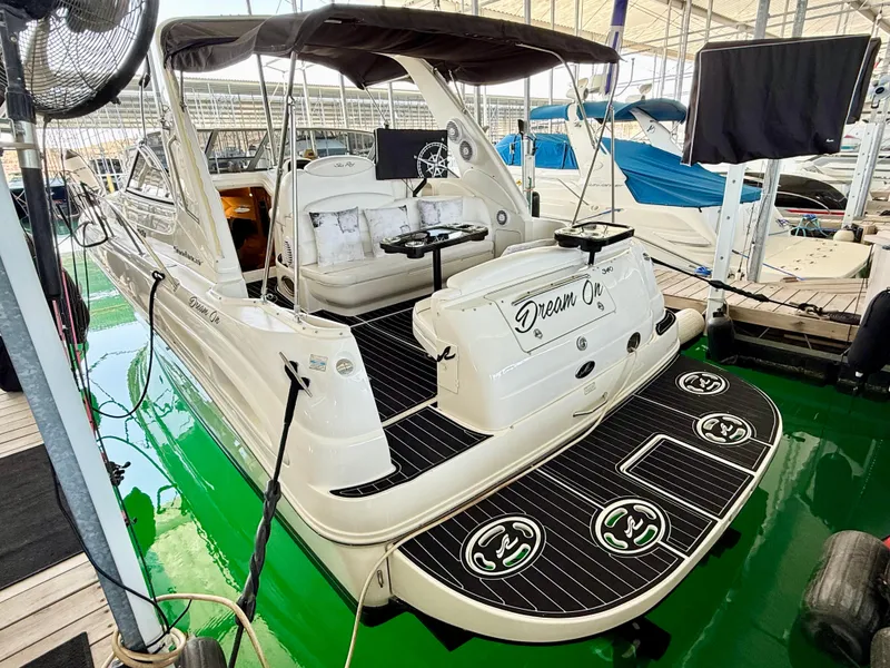 Slide: The Image of 1999 Sea Ray 340 Sundancer boat docked, featuring spacious deck and seating area. - 6